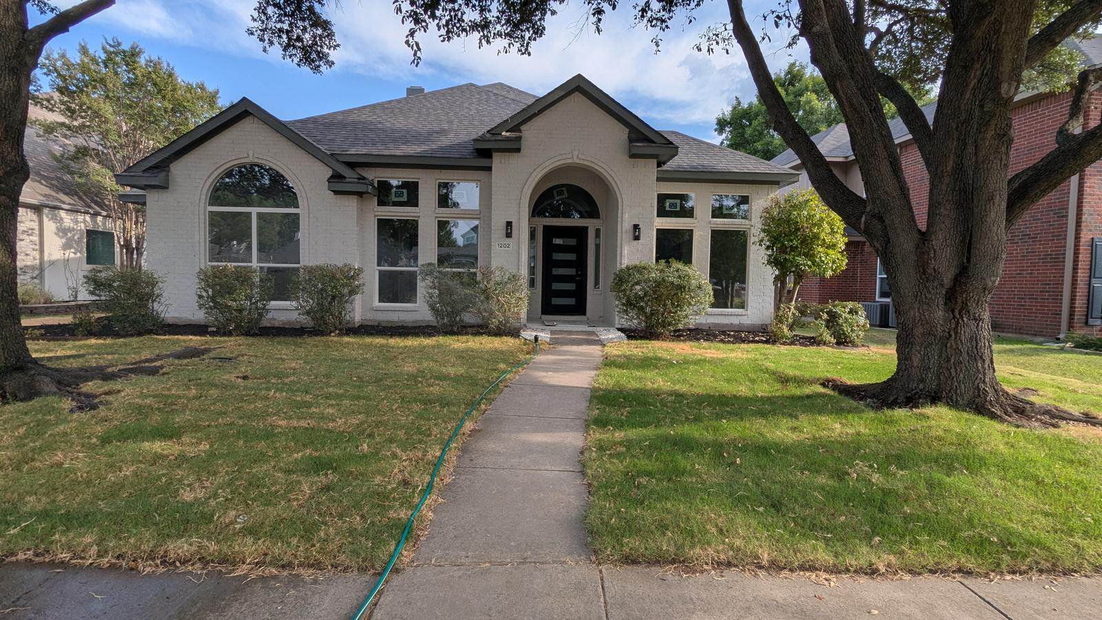 After: painted brick, fresh landscaping, and a finished front elevation